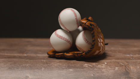 Close-Up-Studio-Baseball-Still-Life-With-Balls-In-Catchers-Mitt-On-Wooden-Floor